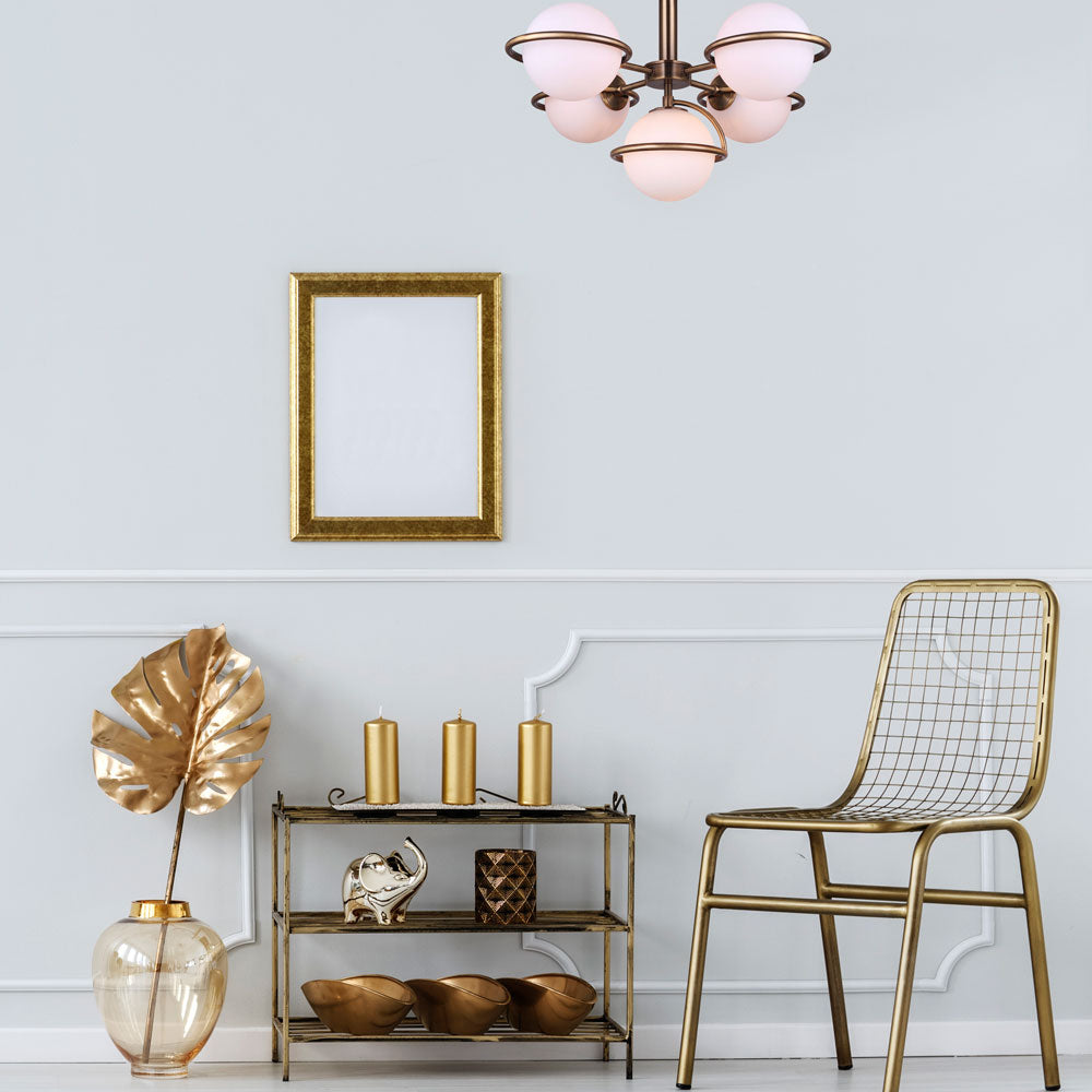 photo of a small vinette, gold chair, gold picture frame, gold table with decorative items, light grey painted wall, and hung is a semi flush, five light, gold finish with five flat opal globes in a mid century style