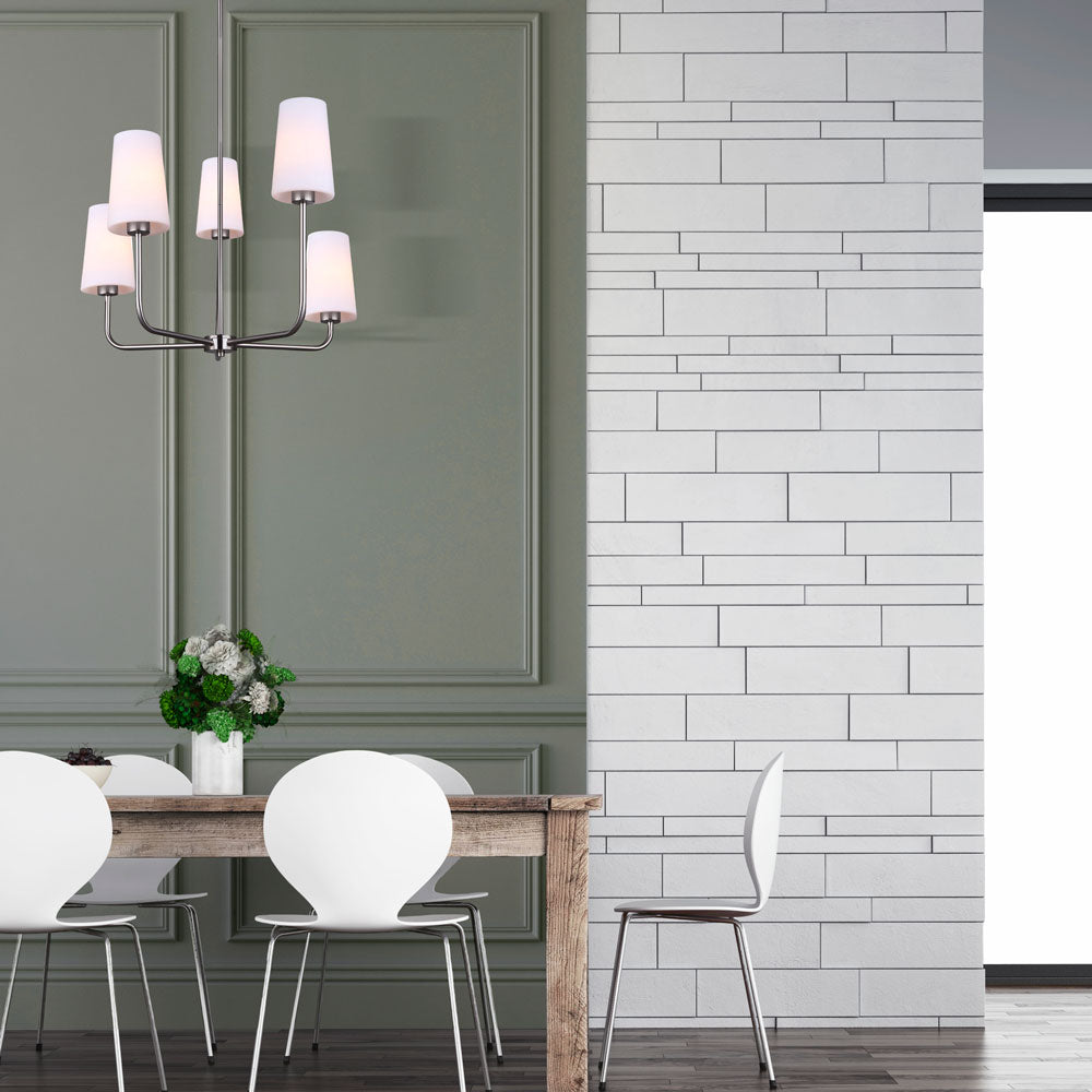 photo of a dining room, with a wooden dinning room table, white chairs, medium grey walls and tile walls with a photo of a 5 light pendant in a brushed nickel finish and 5 flat opal glass shades hanging from the ceiling