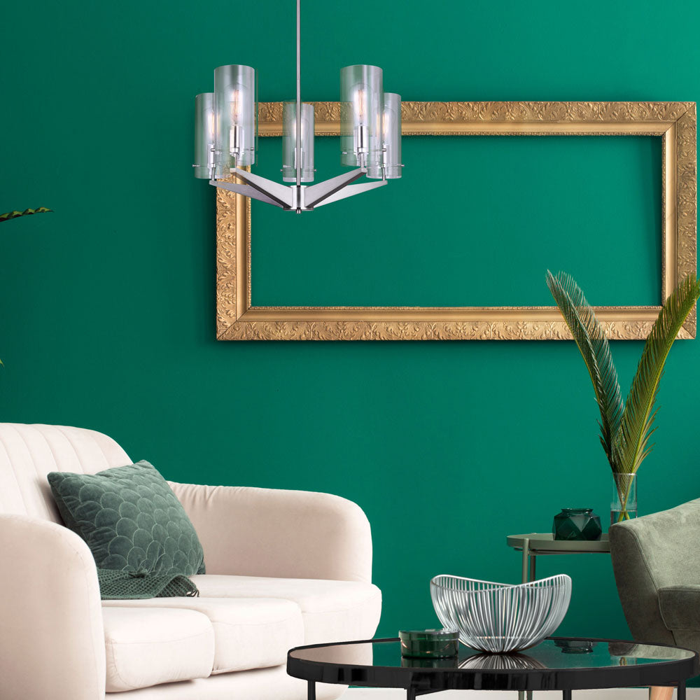 photo of a living room with a large white chair, black and glass round table, wall is painted bright green, gold empty picture frame is hung on the wall, hung from the ceiling is a 5 light chandelier in brushed nickel finish, with five clear glass shades