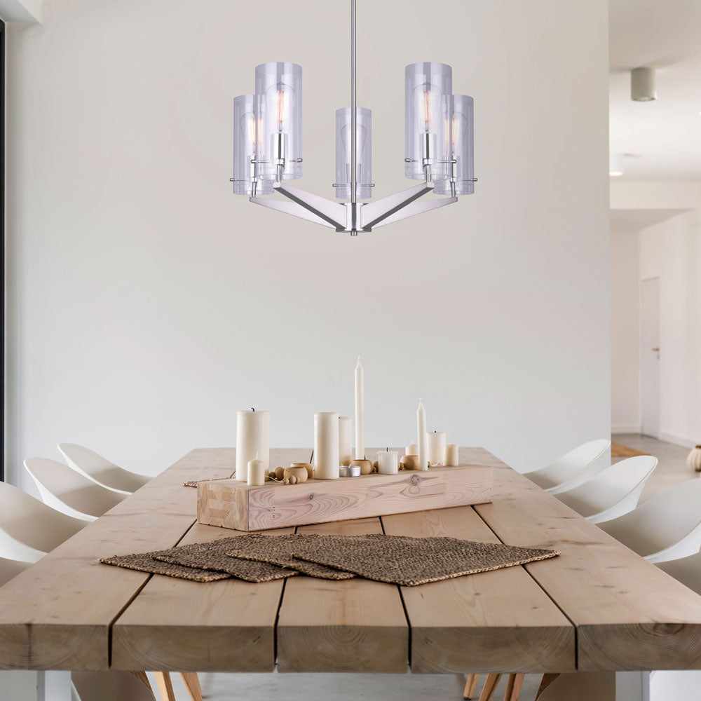 dinning room with wooden dinning room table and six white chairs, candles and placemats in the center of the table. Hung above the table is a five light chandelier in brushed nickel finish and five clear glass shades